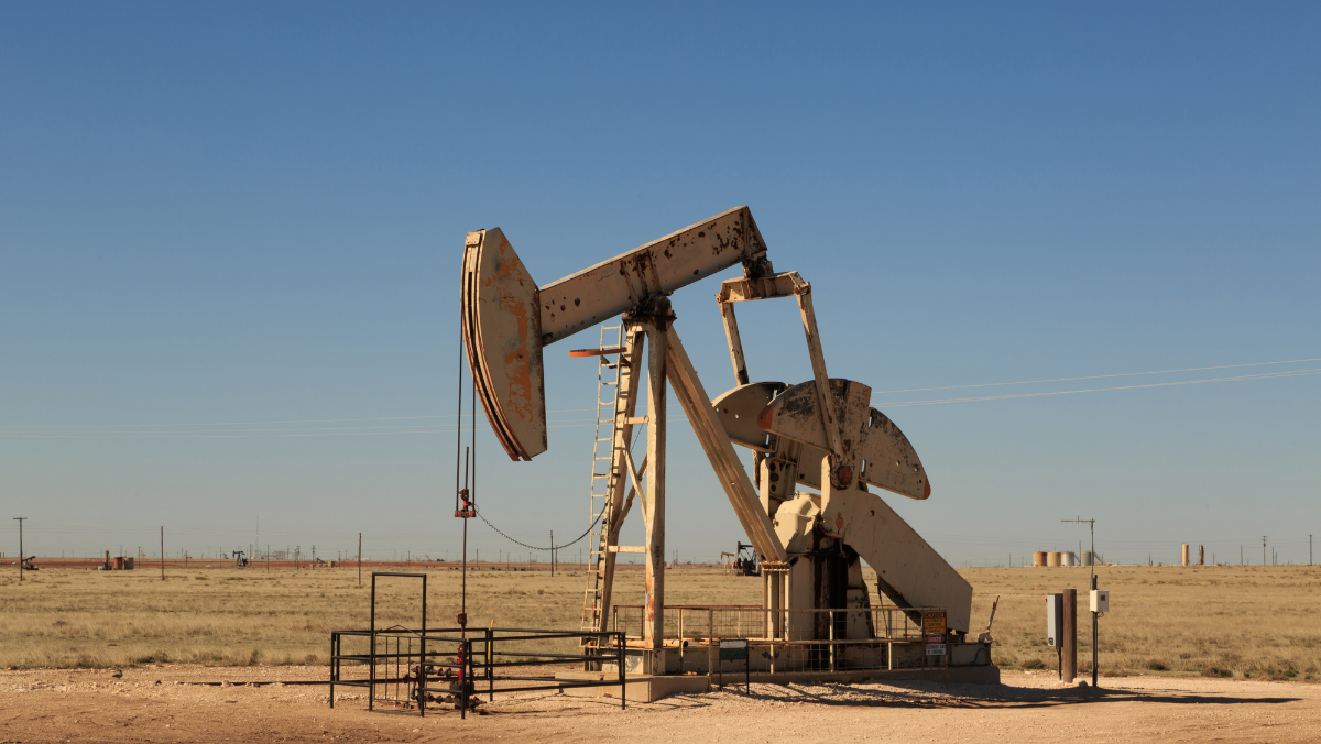 Oil pumpjack operating in a dry shale field under clear blue sky