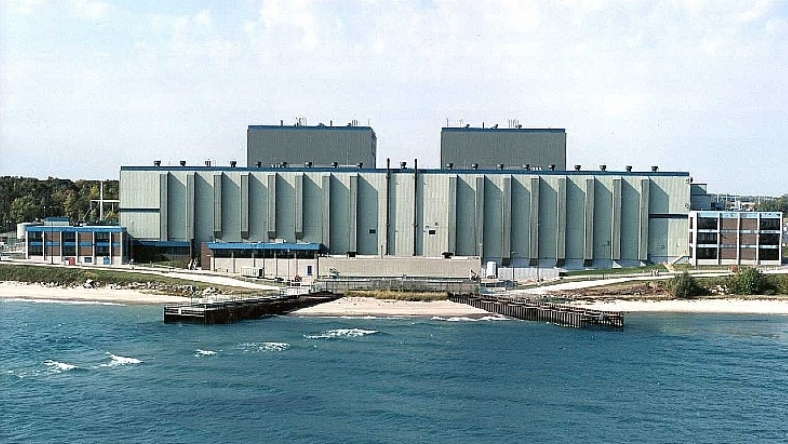 Large industrial facility located on waterfront with dock extending into open water